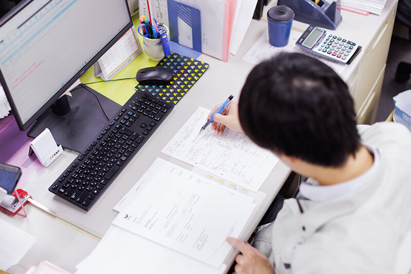 パソコンの前で書類を確認する社員